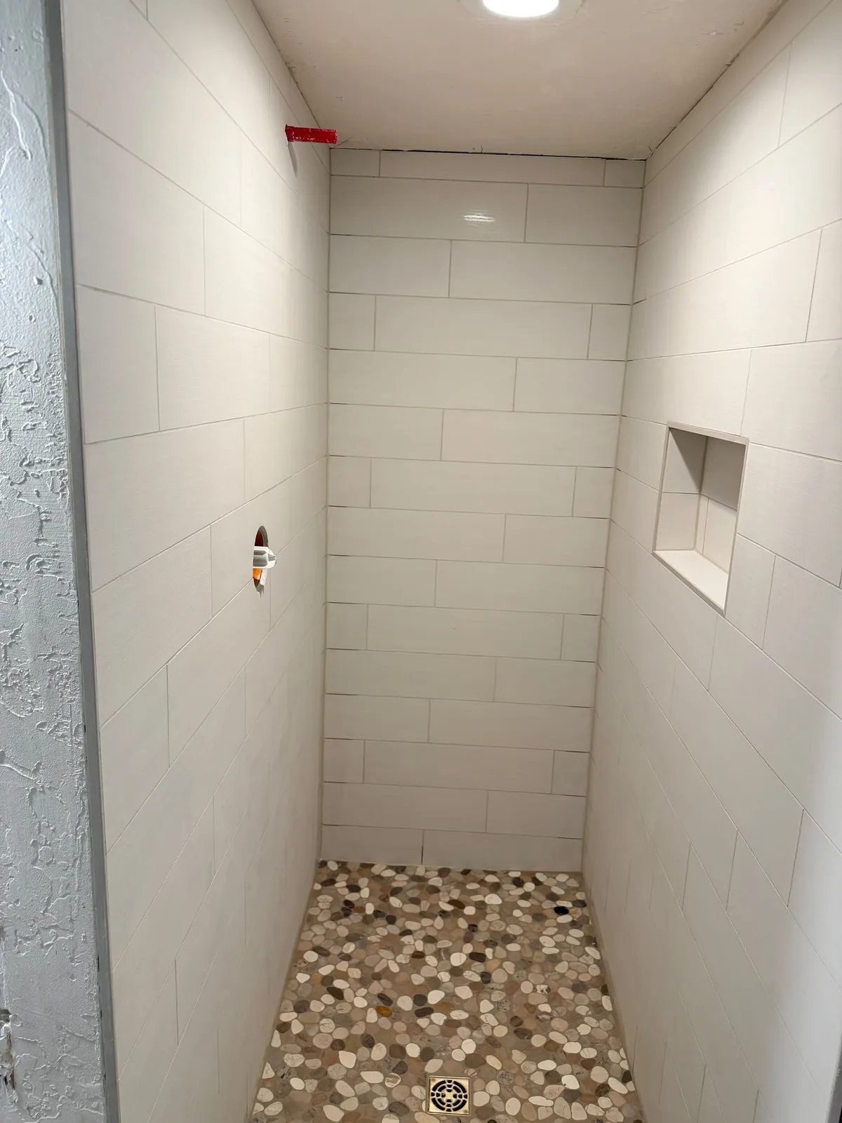 White tile shower with pebble floor and glass door